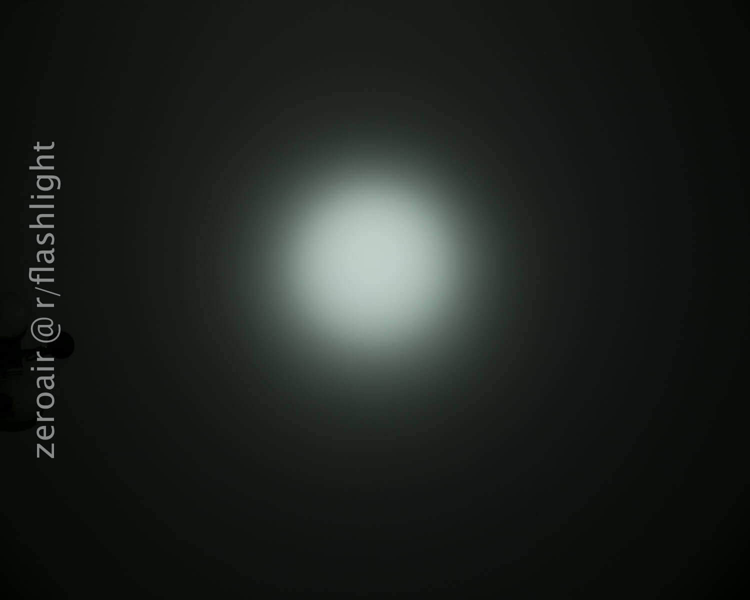 A circular beam of white light shines on a dark surface. The words zeroair @r/flashlight are written vertically along the left side of the image.