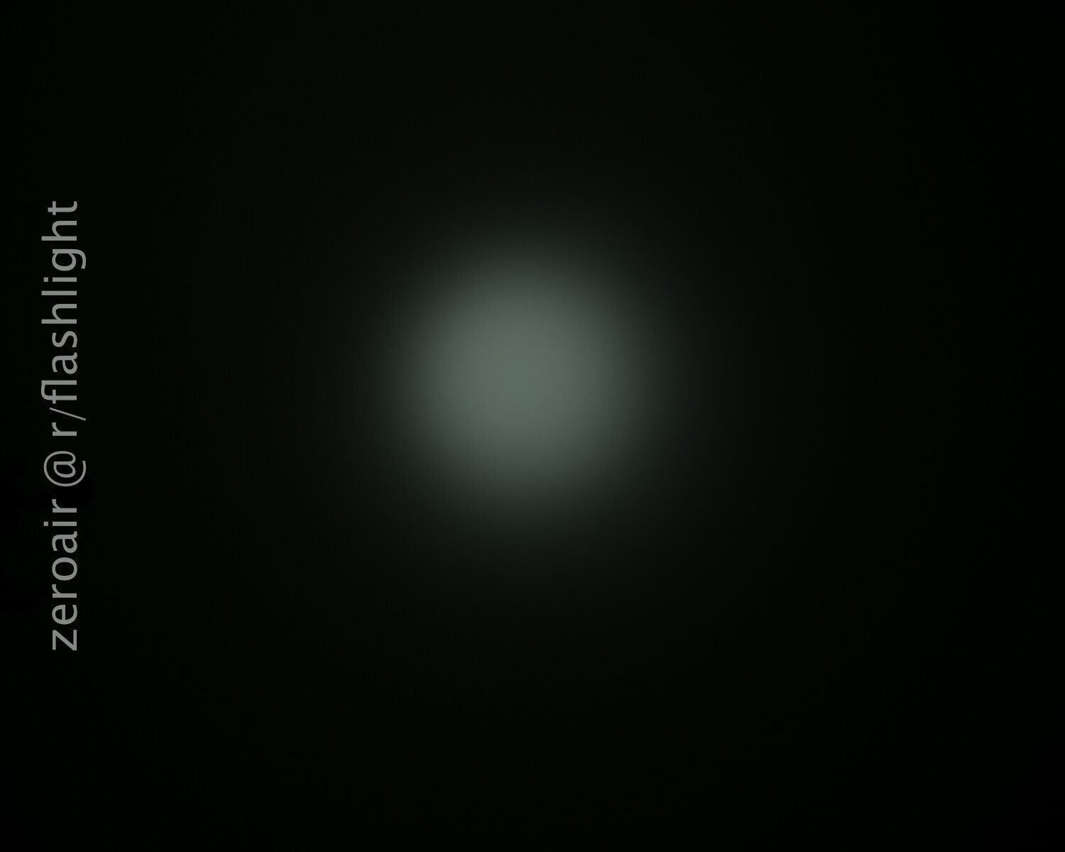 A dim, circular beam of light is visible in the center of a dark background. The text zeroair @ r/flashlight appears vertically along the left side of the image.