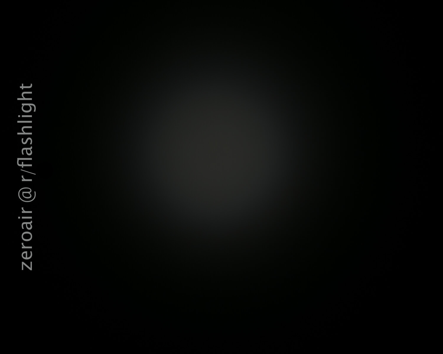 A dim, circular light spot is visible in the center against a dark background. The text “zeroair @ r/flashlight” runs vertically along the left side of the image.