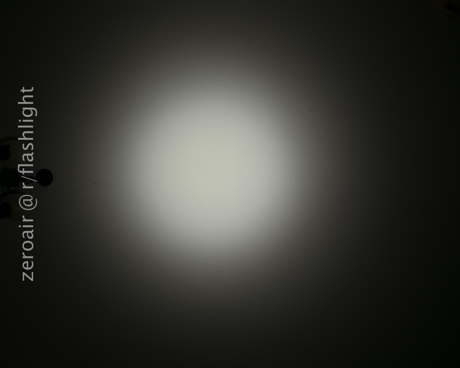 A bright circular beam of white light is focused in the center against a dark background. The text zeroair @ r/flashlight appears vertically on the left side of the image.