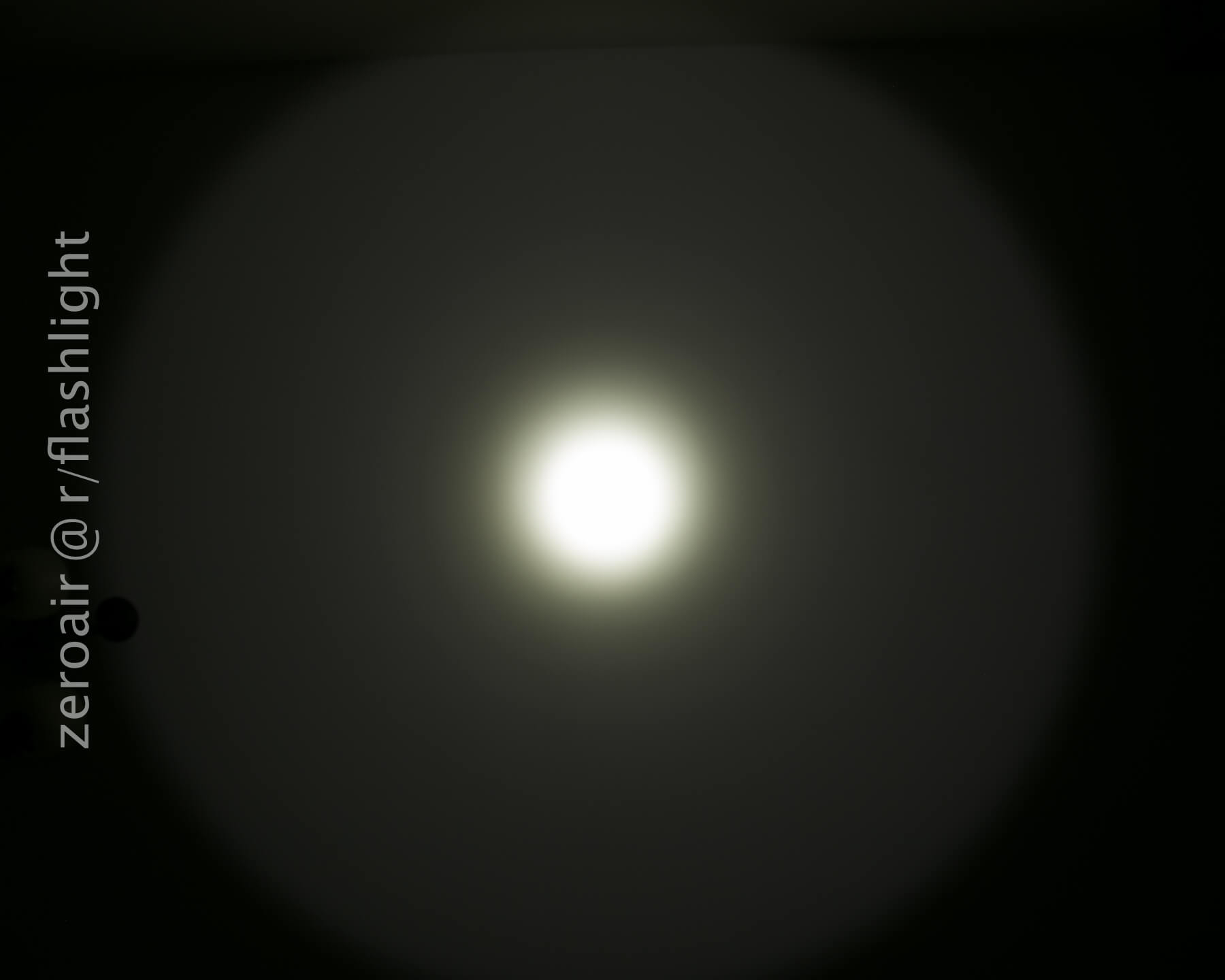A bright white circular light shines in the center of a dark background, creating a gradual fade outward. The text zeroair @ r/flashlight is vertically aligned on the left side of the image.