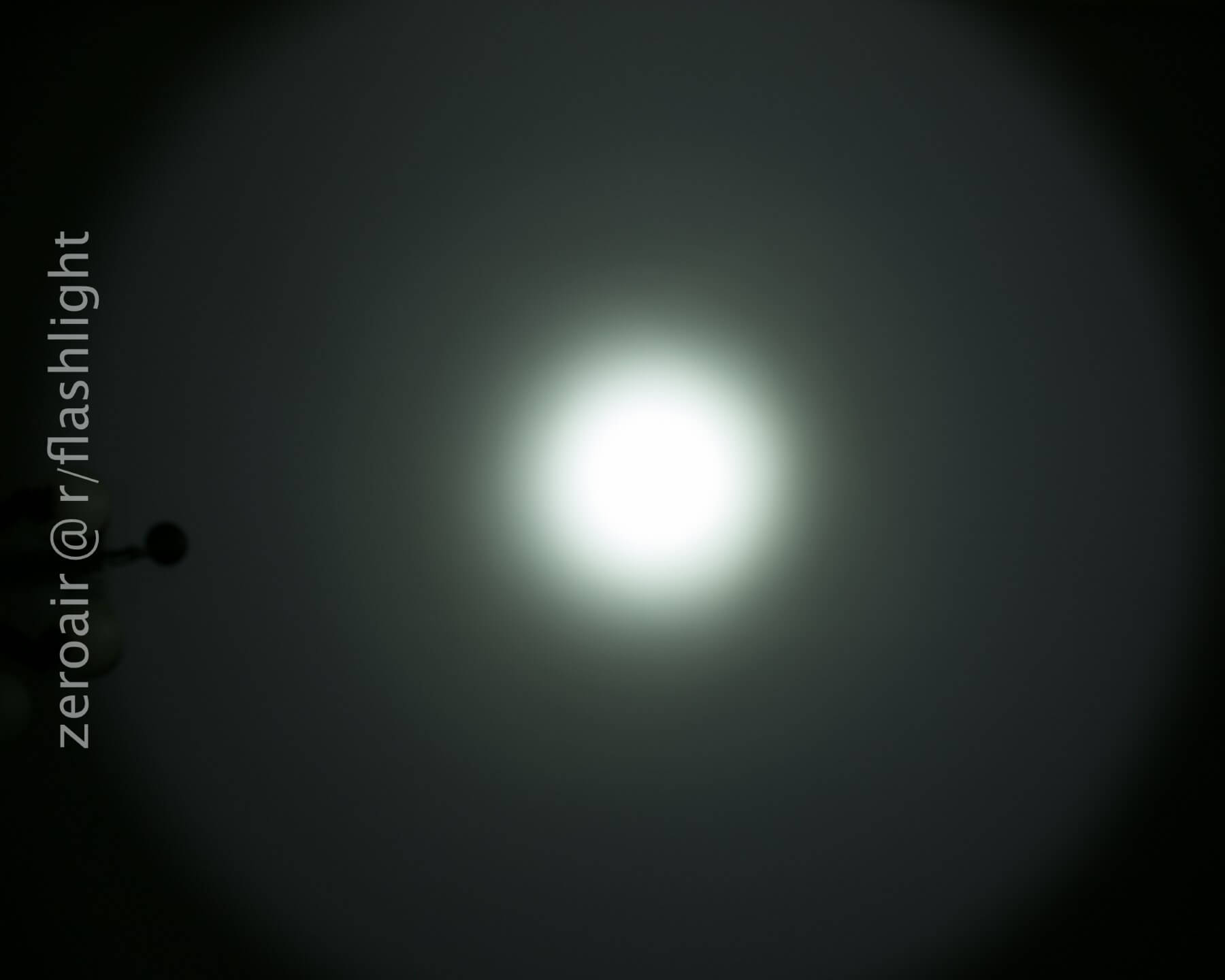 A bright white circular light is centered against a dark background. The light gradually fades to black at the edges. The text zeroair @ r/flashlight is vertically aligned on the left side.