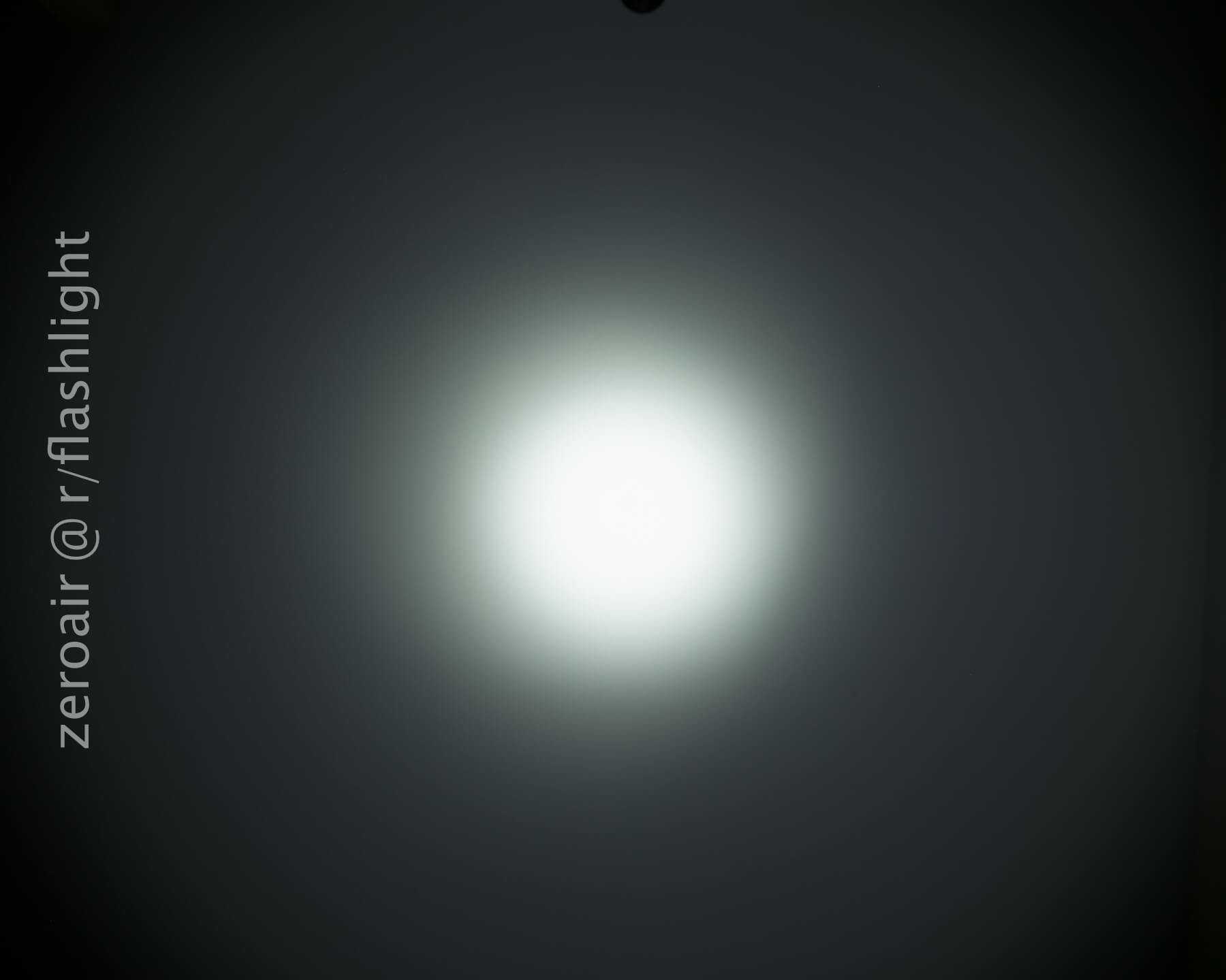 A circular white beam of light is centered on a dark background, with a gradient transitioning from bright in the middle to dimmer at the edges. Text along the left side reads zeroair @ r/flashlight.