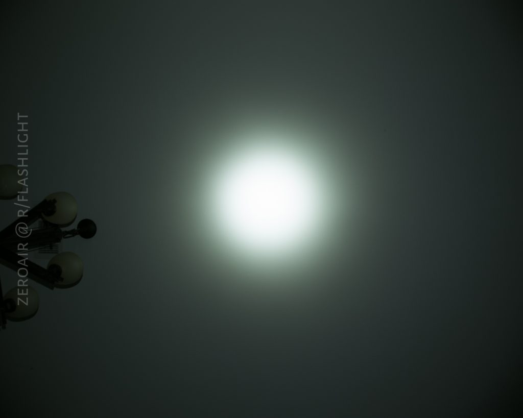 A bright circular light shines in the center of a dark background. A cluster of lamp posts is visible in the lower left corner. The words ZEROAIR @ RFLASHLIGHT are written vertically along the left side.