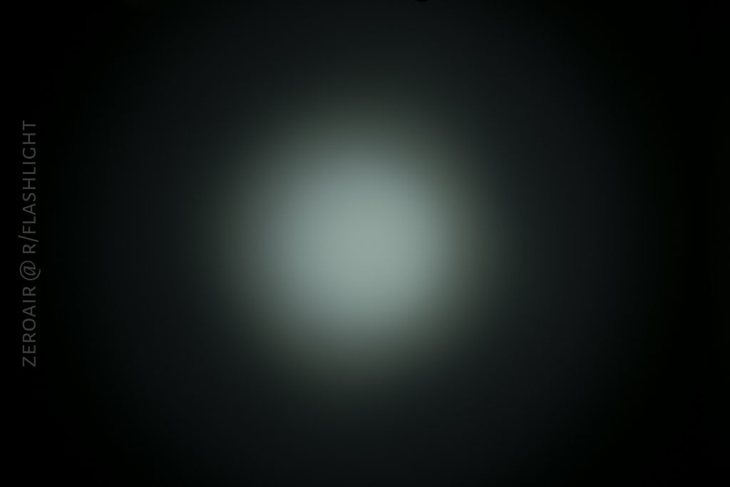 A circular beam of light with a bright center fades into darkness at the edges against a black background. Text along the left side reads, ZEROAIR @ R/FLASHLIGHT.