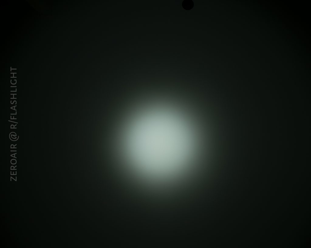 A circular white beam of light is centered against a dark background, showing a bright spot with gradual fading at the edges. The text ZEROAIR @ R/FLASHLIGHT appears vertically along the left side.