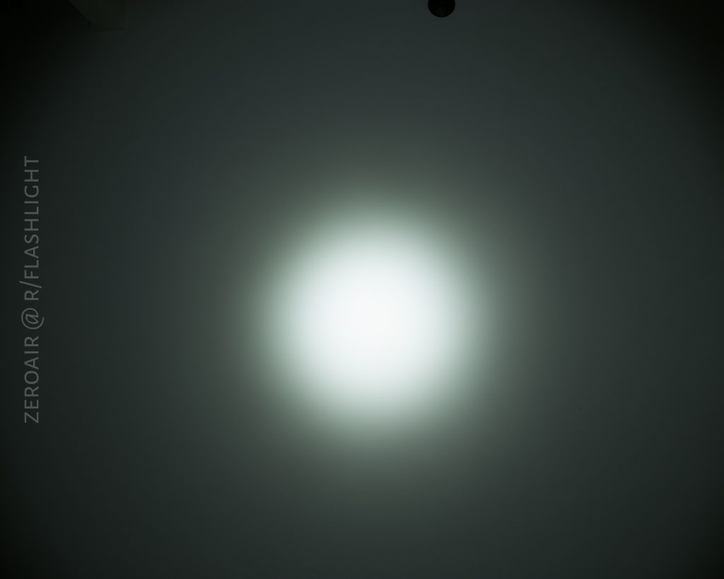 A bright white spotlight shines on a dark surface, creating a circular gradient from the center outward. The text “ZEROAIR @ R/FLASHLIGHT” is vertically placed on the left side.