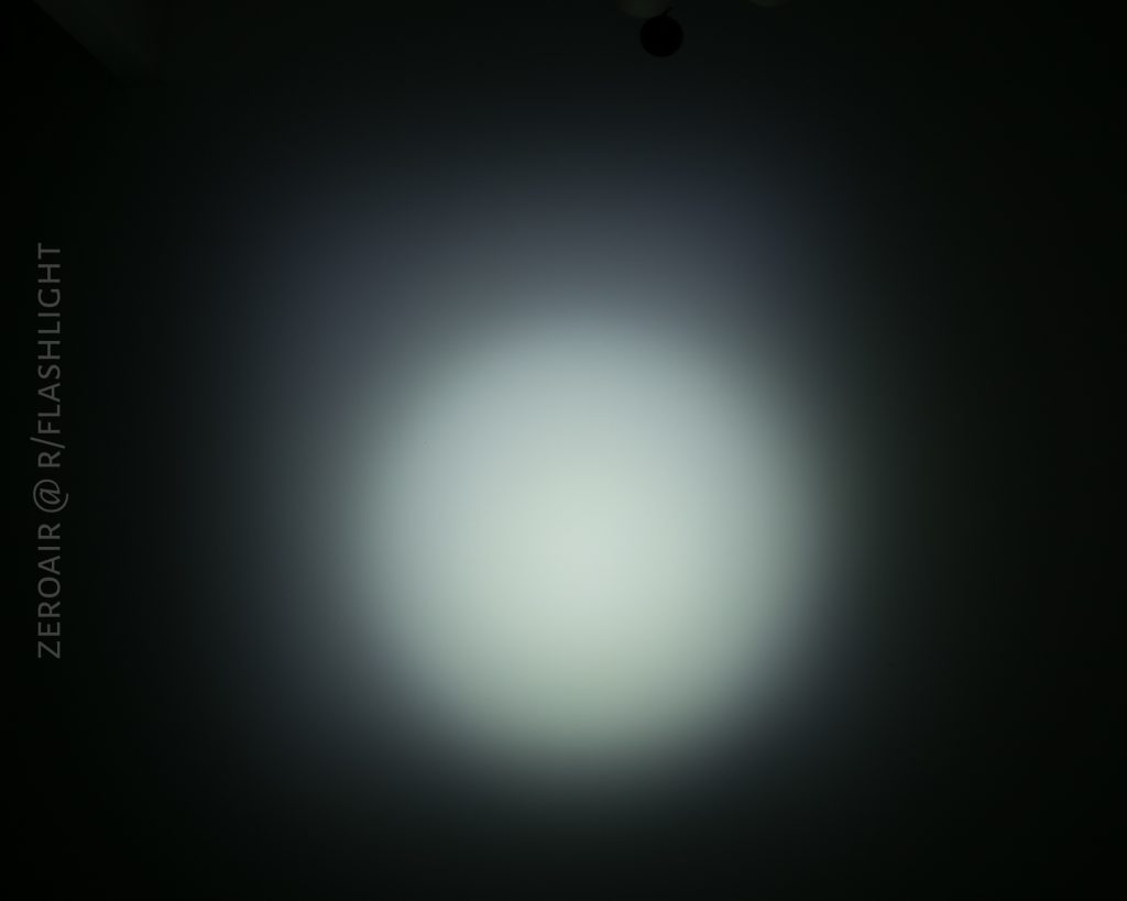 A circular beam of white light, reminiscent of the Olight S1Rv2, shines on a dark surface with a soft gradient fading outward. The text ZEROAIR @ R/FLASHLIGHT appears vertically along the left side.