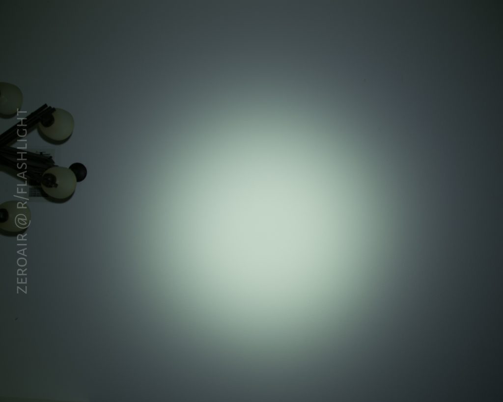 A dimly lit ceiling with a central bright spot of light, likely from a flashlight, and a cluster of light bulbs partially visible in the upper left corner. Text runs vertically along the left side.