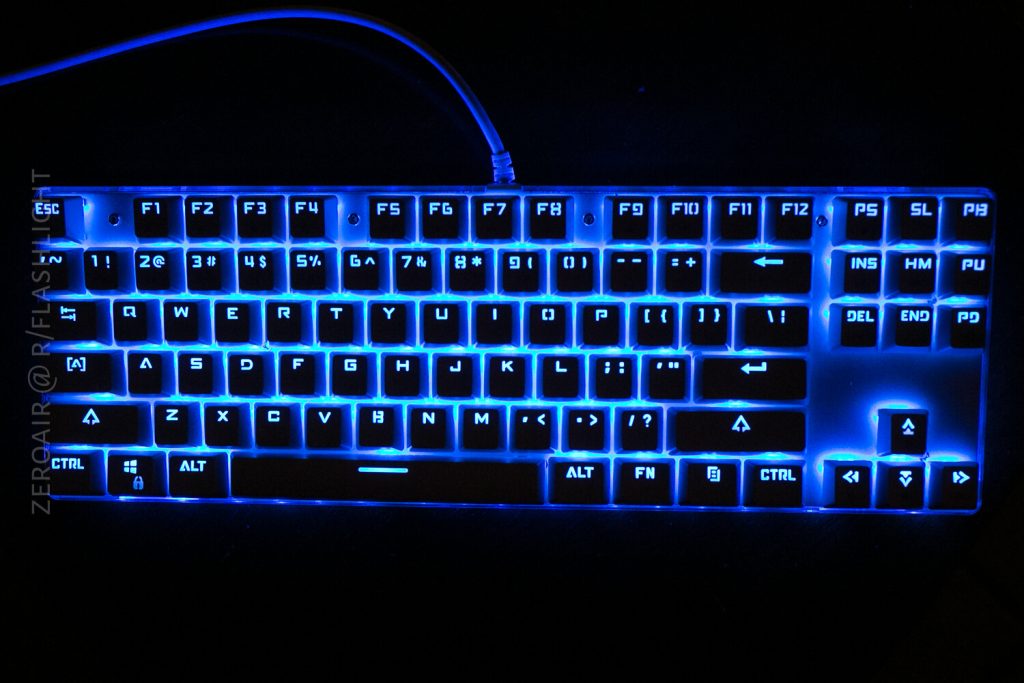 A computer keyboard with blue backlighting is shown from above. The keys are clearly visible and the keyboard is connected by a cable at the top.