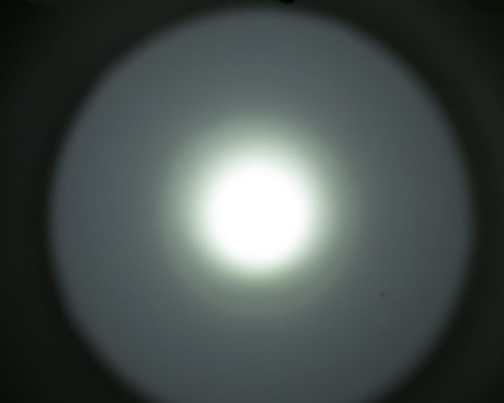 A bright white circular light is centered against a darker background, creating a halo effect with gradually fading edges.