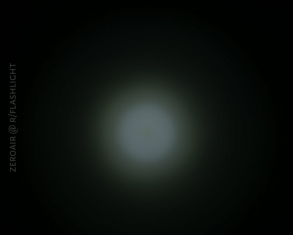 A dim, circular beam of light is visible at the center of a dark background. The light gradually fades outwards. Text reading ZEROAIR @ R/FLASHLIGHT appears vertically on the left side.