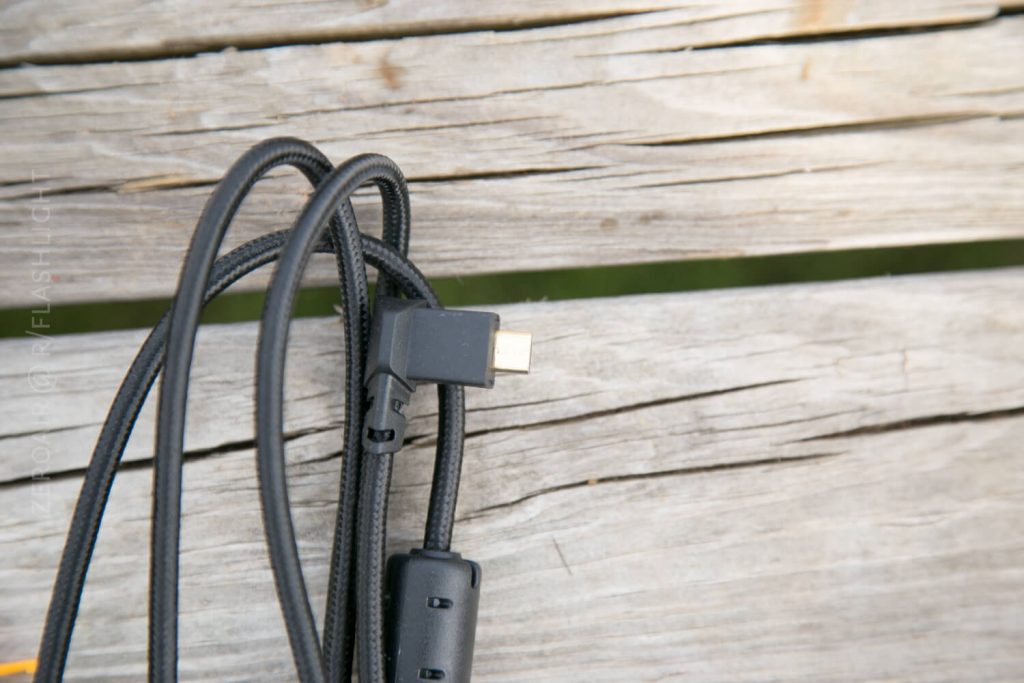 A black braided USB-C cable with an angled connector rests on a weathered wooden surface.