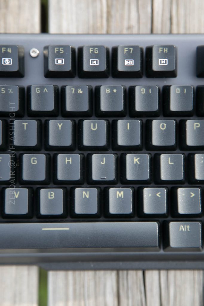 A close-up view of the upper right section of a black computer keyboard, showing function keys F4 through F10 and alphanumeric keys from Y to Alt, placed on a wooden surface.