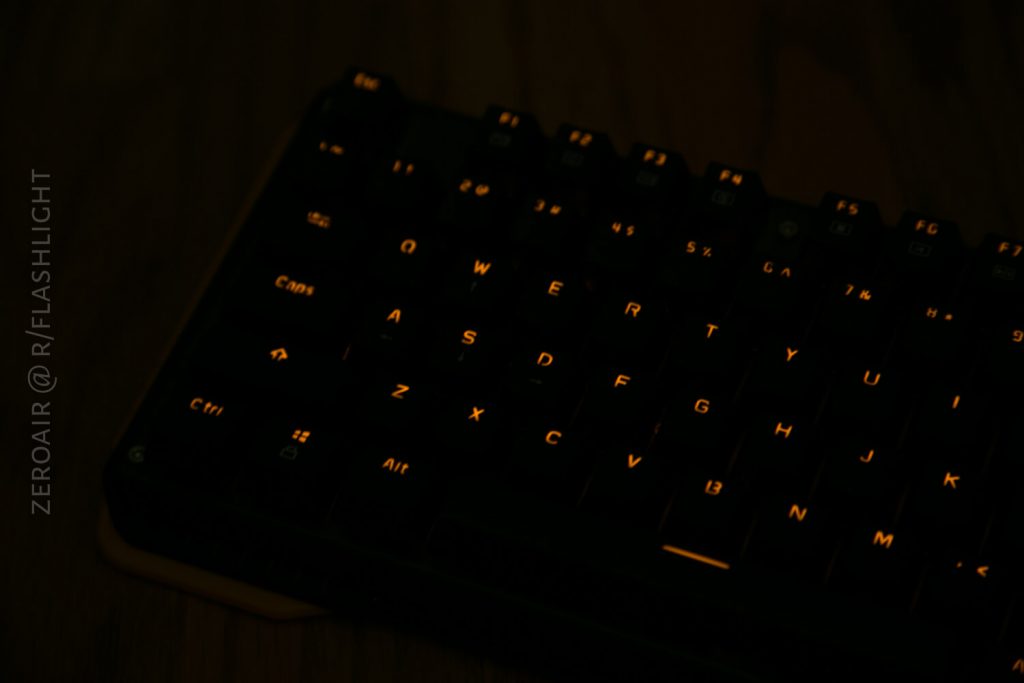 A dark image of a keyboard with faintly illuminated keys. The letters QWERTY, A, S, D, and Z are most visible. Text on the left reads ZEROAIR @ R/FLASHLIGHT.