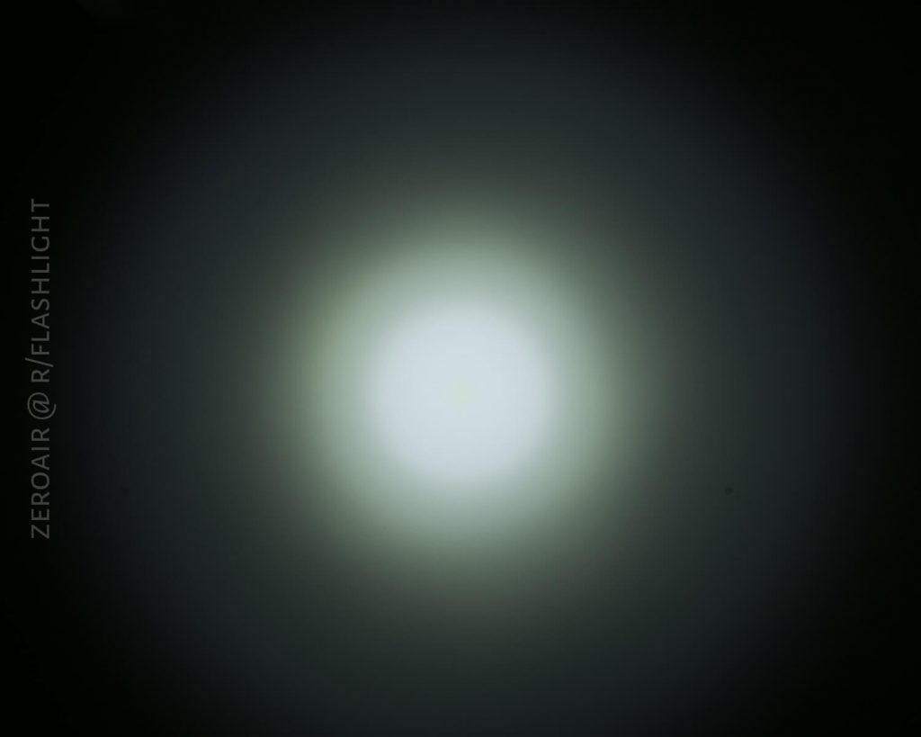 A circular white light with a bright center and a gradient fading to dark around the edges, likely from a flashlight beam, on a dark background. The text “ZEROAIR @ R/FLASHLIGHT” appears vertically on the left side.