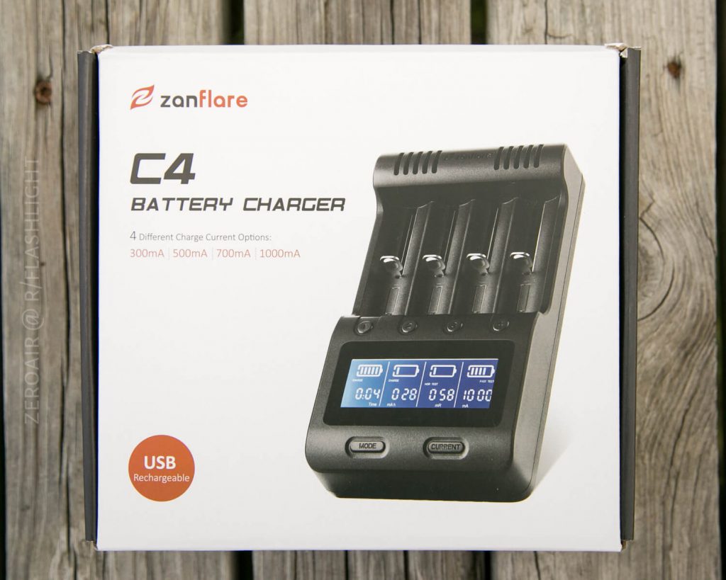 A box for a zanflare C4 battery charger is shown against a wooden background. The box features an image of the charger with four battery slots, a digital display, and information about USB charging and current options.
