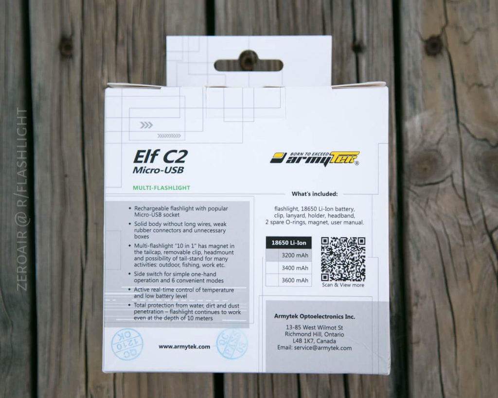 The back of a box for the Armytek Elf C2 Micro-USB flashlight is shown on a wooden surface, displaying product features, specifications, a QR code, and the manufacturers contact information.