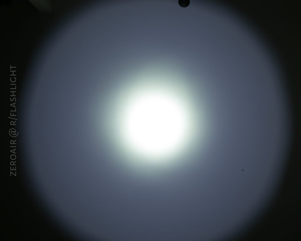 A bright white flashlight beam forms a circular pattern on a dark wall, with a concentrated center and faded edges. The text ZEROAIR @ R/FLASHLIGHT appears vertically on the left side.