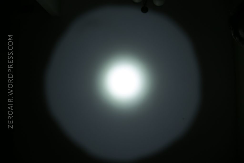 A circular, bright white flashlight beam is projected onto a dark surface, creating a gradient halo effect. The text ZEROAIR.WORDPRESS.COM appears vertically along the left side of the image.