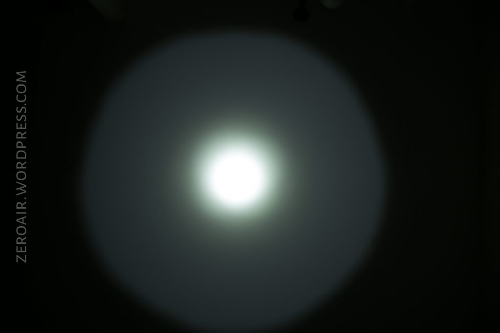 A bright circular beam of white light with a softer outer halo is projected onto a dark background. The text “ZEROAIR.WORDPRESS.COM” appears vertically on the left side.