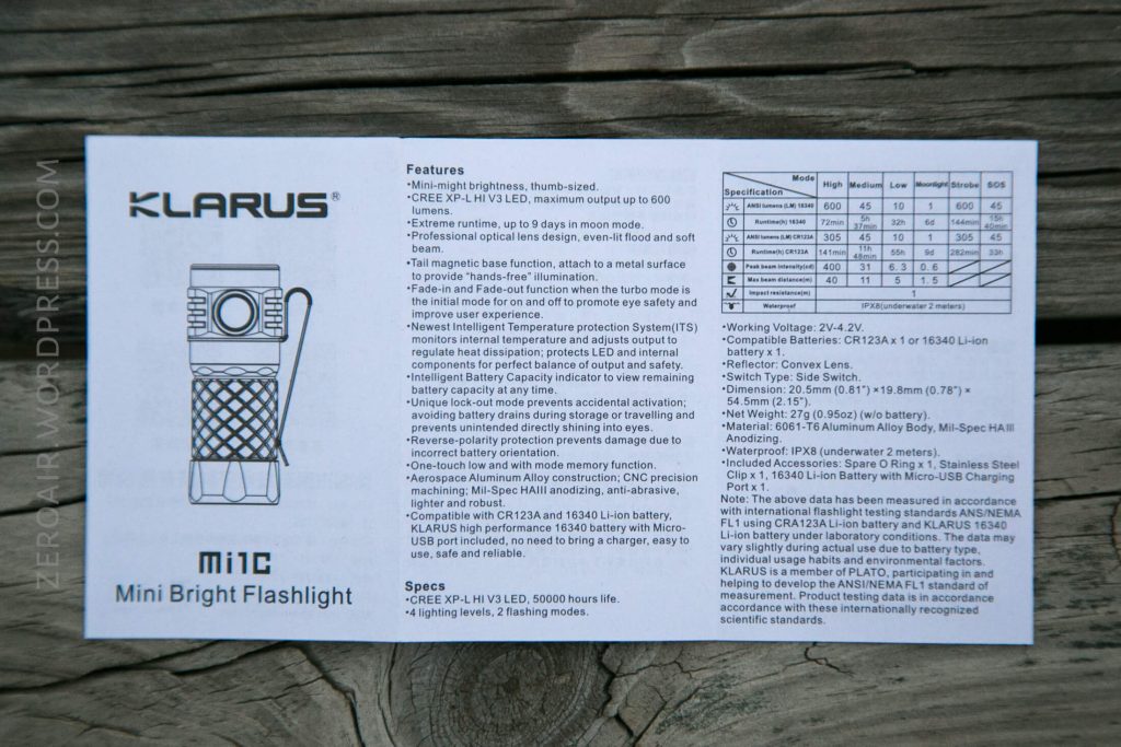 A product information card for the Klarus Mi1C Mini Bright Flashlight, showing its image, features, specifications, and technical details, placed on a wooden surface.