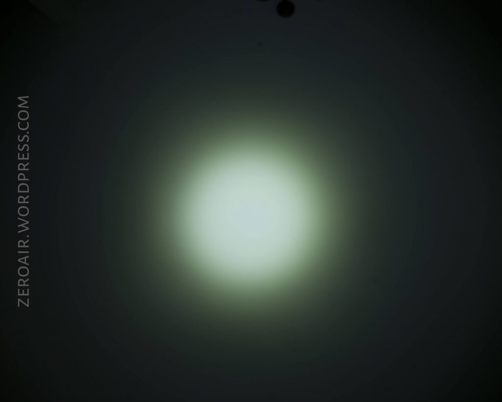 A flashlight beam creates a circular, bright white spot with a soft gradient fading to dark edges. The background is dark. The text ZEROAIR.WORDPRESS.COM appears along the left edge.