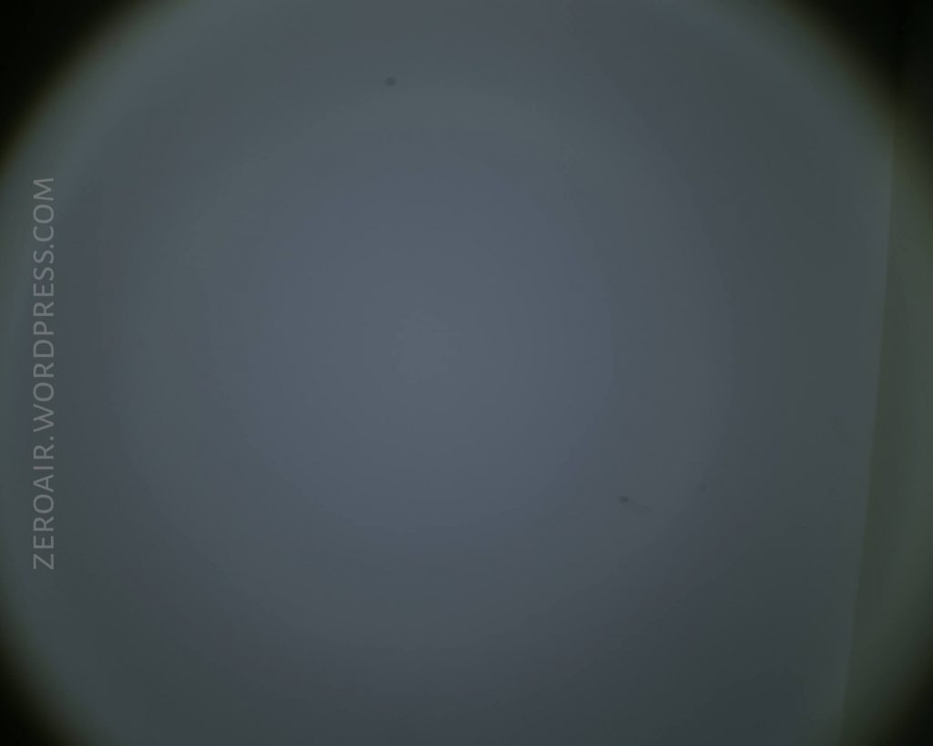 Out-of-focus image with a circular dark border, a faint gradient from light blue to gray in the center, and the text ZEROAIR.WORDPRESS.COM vertically along the left side.