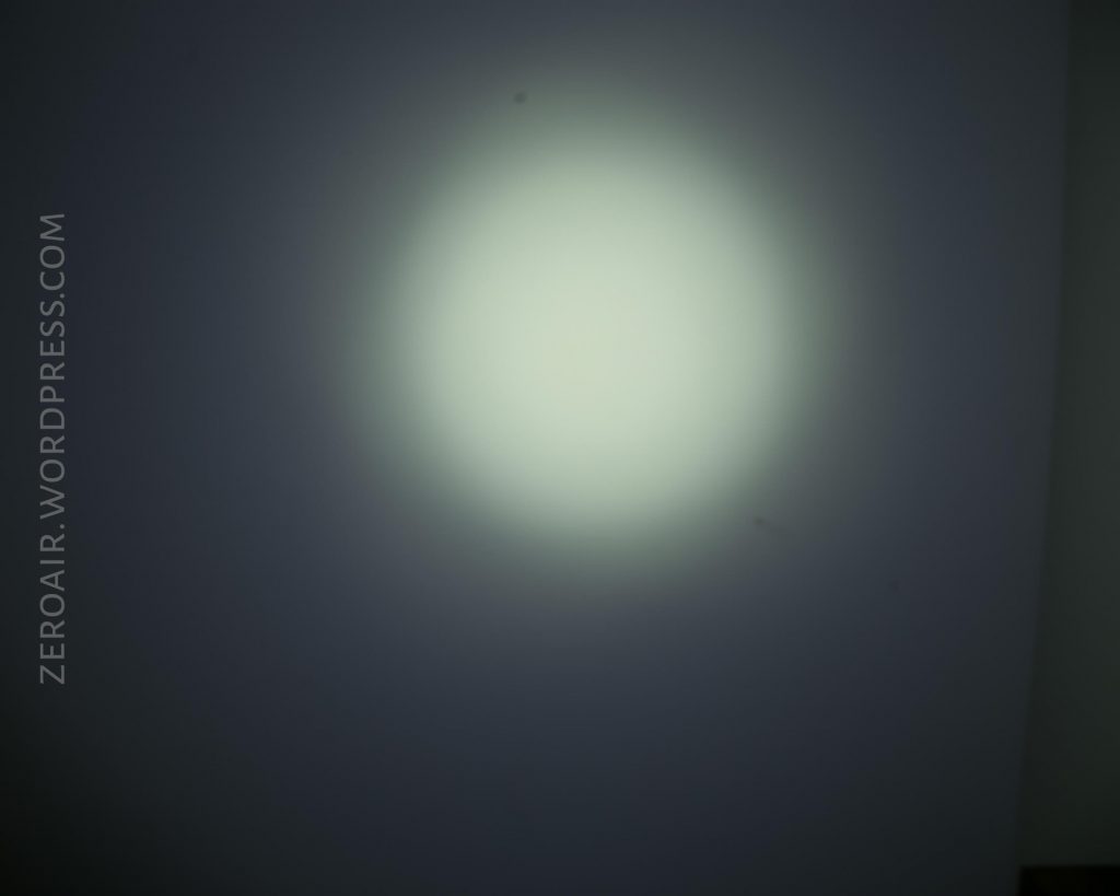 A circular white beam of light shines on a plain gray wall, creating a soft gradient. The words ZEROAIR.WORDPRESS.COM appear vertically along the left side of the image.