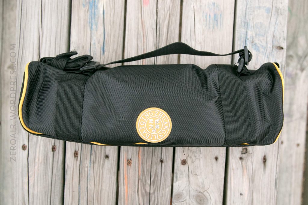 A black and yellow sports bag with a shoulder strap and the logo Zhong Zhen Sha printed in gold on the side, placed on a weathered wooden surface.
