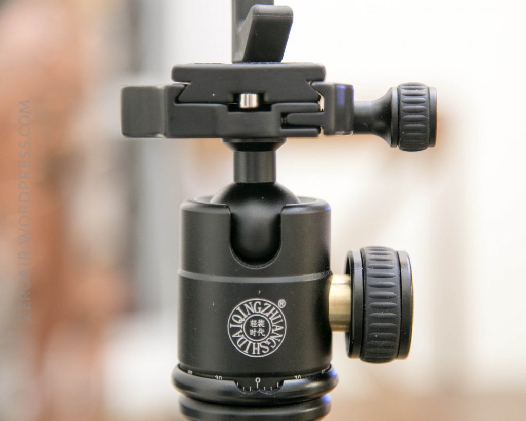 Close-up of a black tripod ball head with adjustment knobs and a visible brand logo reading Longwin on the side. The background is out of focus.