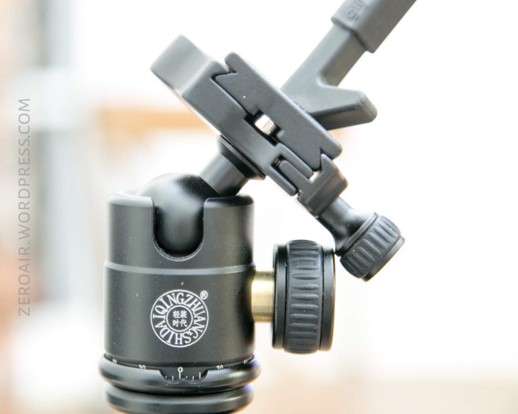 A close-up view of a black Qingzhuangshidian tripod ball head with adjustment knobs and a clamp, mounted on a tripod. The logo and branding are clearly visible on the ball head.