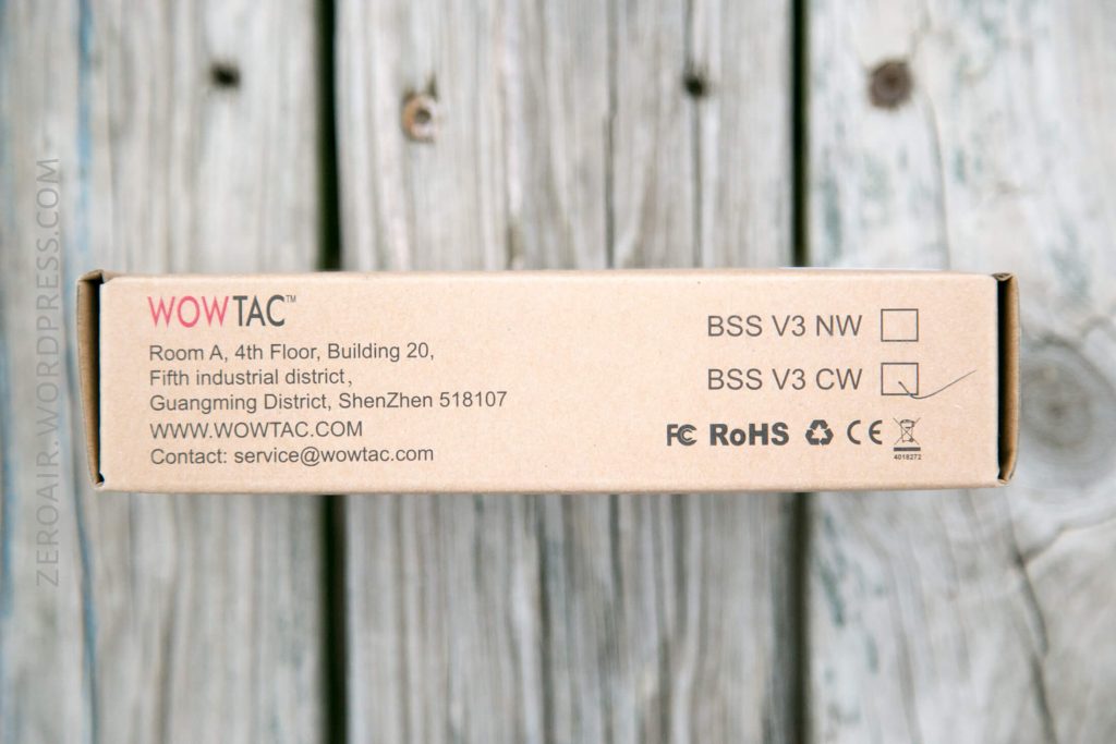 A brown WOWTAC product box showing address, website, email, certification icons, and two checkboxes labeled BSS V3 NW and BSS V3 CW, with the NW option checked. The box is placed on a wooden surface.