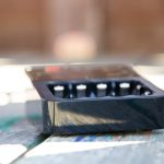 A close-up photo of an empty black plastic tray sitting on a weathered wooden surface. The background is blurred, and ZEROAR.WORDPRESS.COM is faintly visible along the left side of the image.