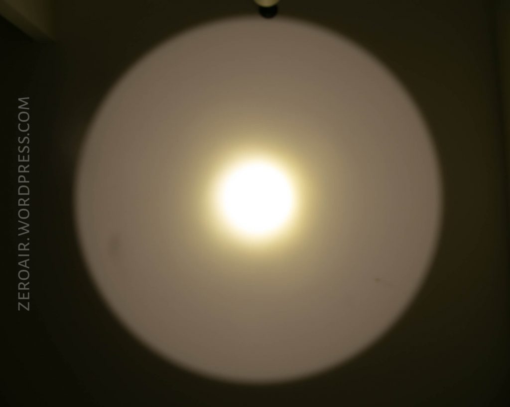 A bright, circular light shines on a wall, creating a defined white halo with a yellowish center. The words ZEROAIR.WORDPRESS.COM appear vertically on the left side of the image.