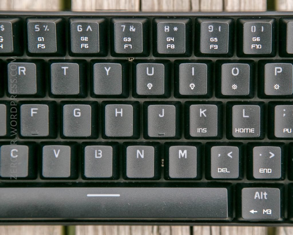 A close-up of the upper right section of a black computer keyboard with visible function, arrow, and delete keys. The wooden surface underneath the keyboard is slightly visible.