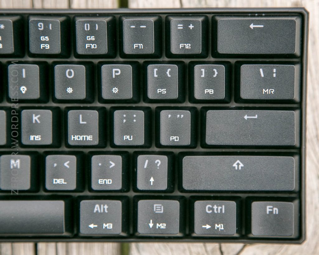 A close-up view of the top right section of a black computer keyboard, showing the function keys, arrow keys, and part of the navigation keys on a wooden surface.