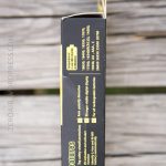 A close-up of a black and yellow product box placed on a wooden surface. The box lists features and compatible device model numbers in yellow text. The top flap of the box is open.