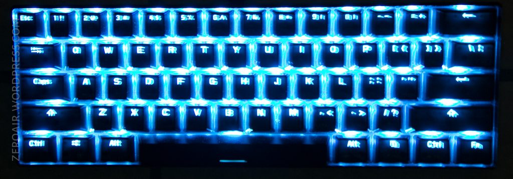 A compact keyboard with blue backlighting, showing clearly illuminated keys including letters, numbers, and function keys. The keys are arranged in a standard QWERTY layout.
