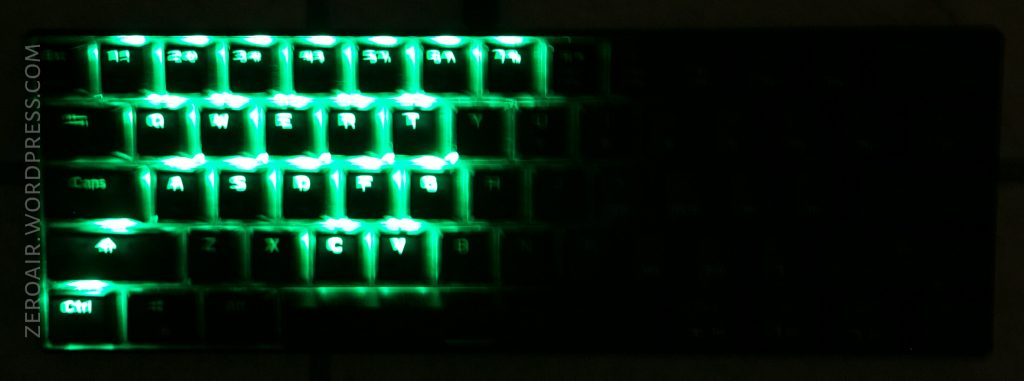 A keyboard with green backlighting showing the numbers 1 to 0 and the letters Q to V clearly illuminated, while other keys are dimly visible. ZEROAIR.WORDPRESS.COM appears vertically on the left side.