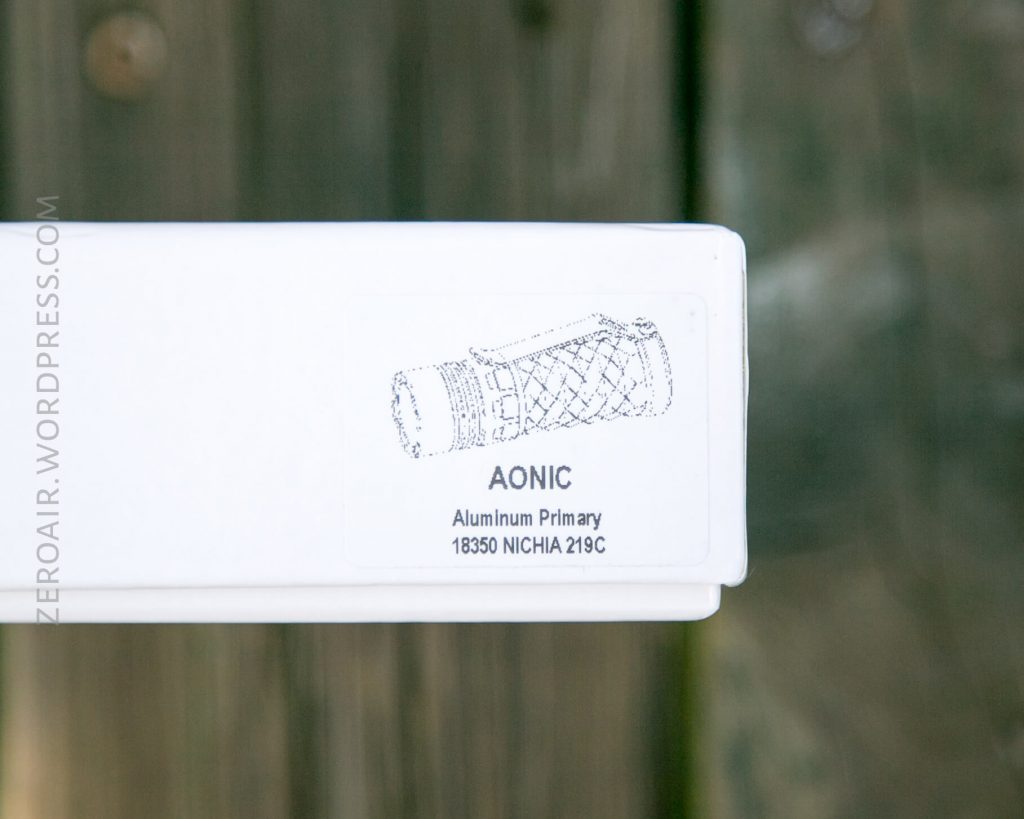 A white box with a black line drawing of a cylindrical object, labeled AONIC Aluminum Primary 18350 NICHIA 219C, is shown. The background is out of focus and features a wooden texture.