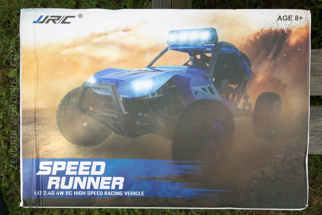 Box for a JJRC Speed Runner 1:12 scale high speed RC racing vehicle, featuring an image of the blue RC car driving on rocky terrain with dust clouds, headlights on, and text indicating it is for ages 8 and up.