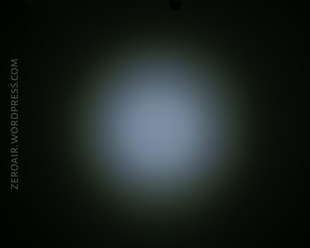 A circular white light beam is projected onto a dark surface, creating a faded halo effect. The background is black, and the text ZEROAIR.WORDPRESS.COM is vertically aligned on the left side.