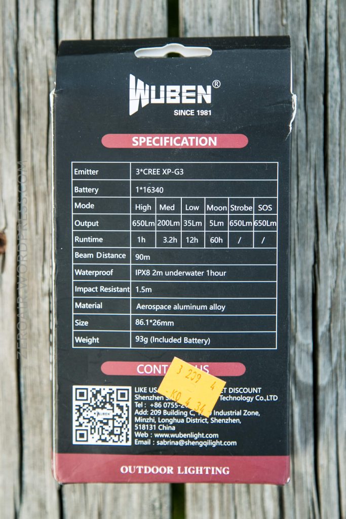 The back of a Wuben flashlight box displays technical specifications, including modes, brightness, battery type, size, weight, and waterproof rating. A yellow price sticker is placed over the contact information section.