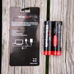 Two black and red rechargeable batteries labeled 3400mAh and USB Rechargeable lie next to their packaging, which shows product features and charging instructions on a wooden surface.