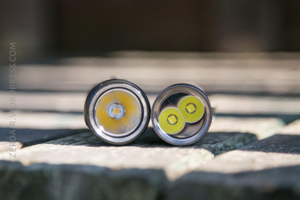 Two flashlight heads are shown side by side on a stone surface, both facing the camera to display their LED emitters. The left flashlight has one LED, and the right flashlight has two.