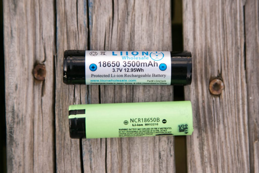 Two cylindrical lithium-ion rechargeable batteries are placed side by side on a wooden surface. The top battery is labeled 18650, 3500mAh, while the lower battery is labeled NCR18650B and is light green.