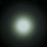 A circular white light beam shines on a dark surface, creating a soft gradient effect. The words ZEROAIR.WORDPRESS.COM appear vertically on the left side of the image.