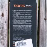 The back of a ROFIS MR30 flashlight box is shown, listing product features, specifications, and a barcode sticker with Made in China and Back printed on it. The box is placed on a wooden surface.