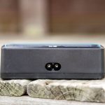 A close-up of a small black electronic device with a two-prong power input, placed on a wooden surface. The background is out of focus. The text AEROAIR.WORDPRESS.COM is visible on the left side.